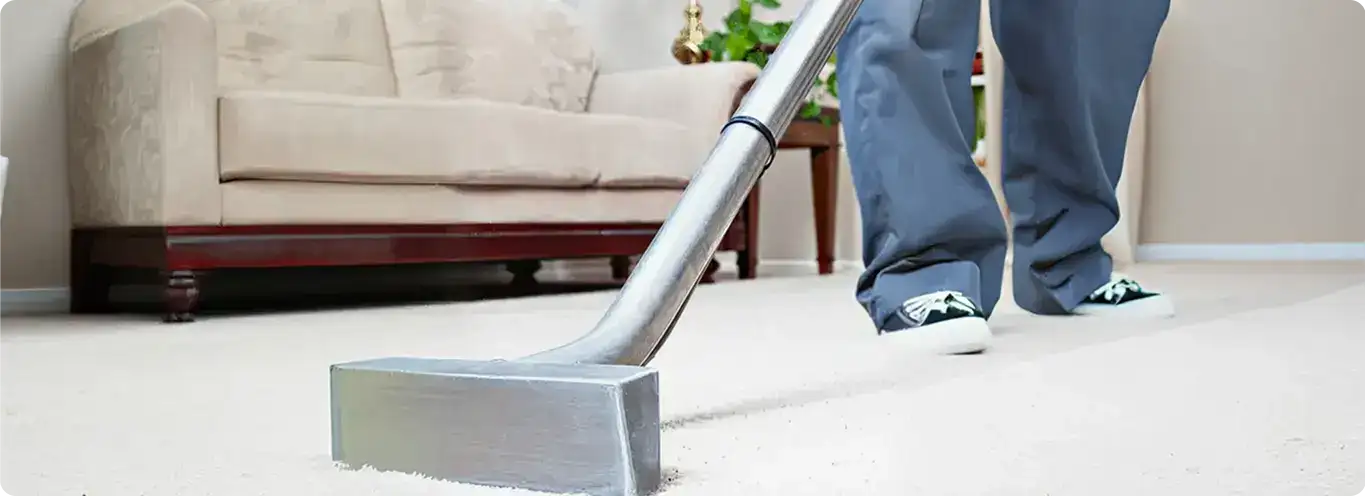 Carpet cleaning technician using a hot-water extraction wand on a light-colored carpet in a living room, Hollywood, FL.